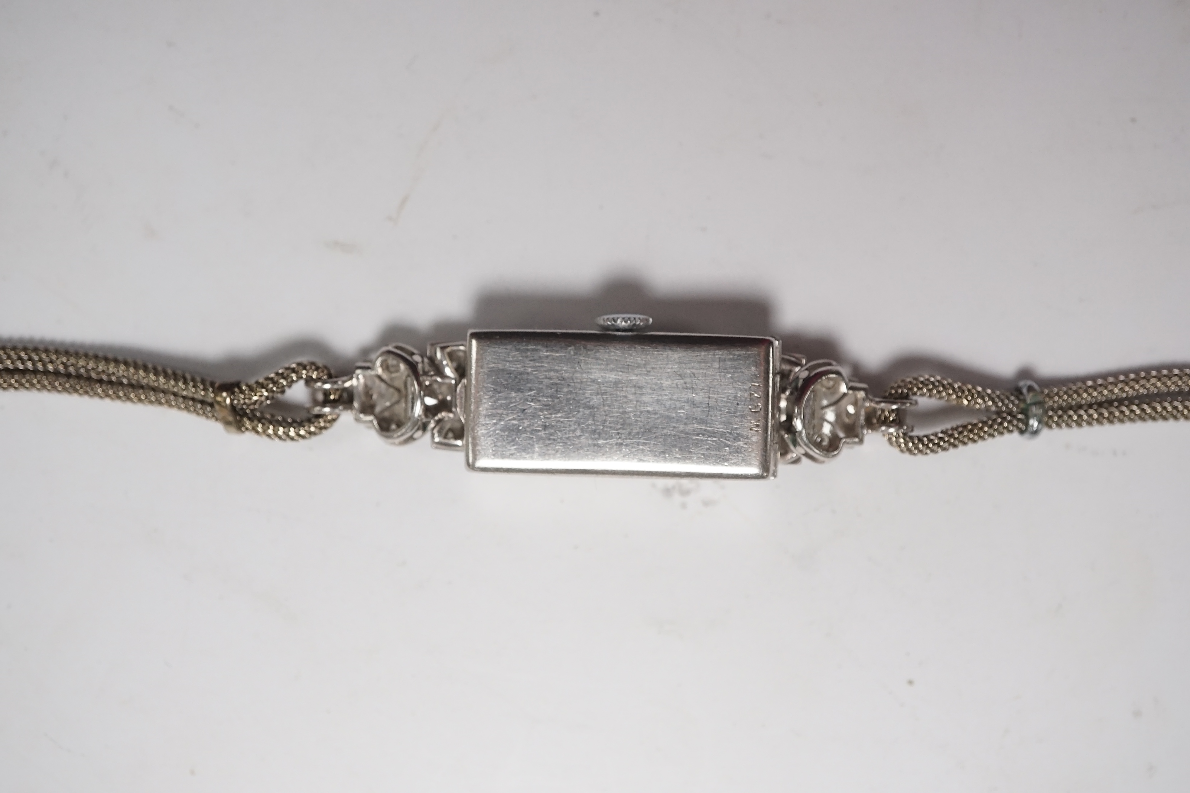 A lady's mid 20th century white metal (stamped platinum) and diamond set manual wind cocktail watch, on a 9ct white metal twin strand bracelet, overall length 16.5cm, gross weight 17.6 grams/ Condition - fair to good